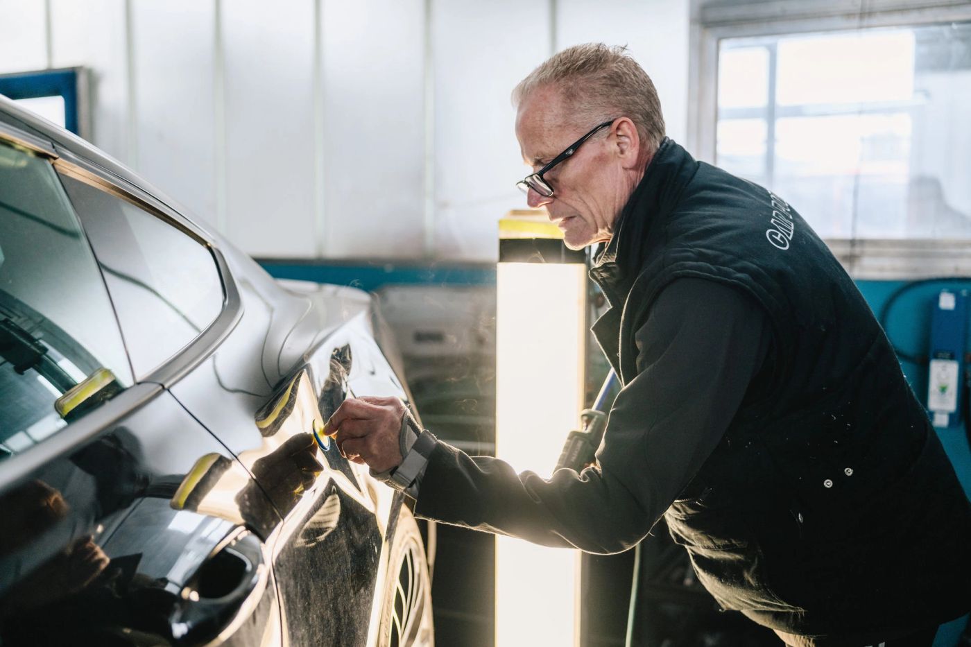 Mitarbeiter von Alicke prüft den Lack an einer Autotür
